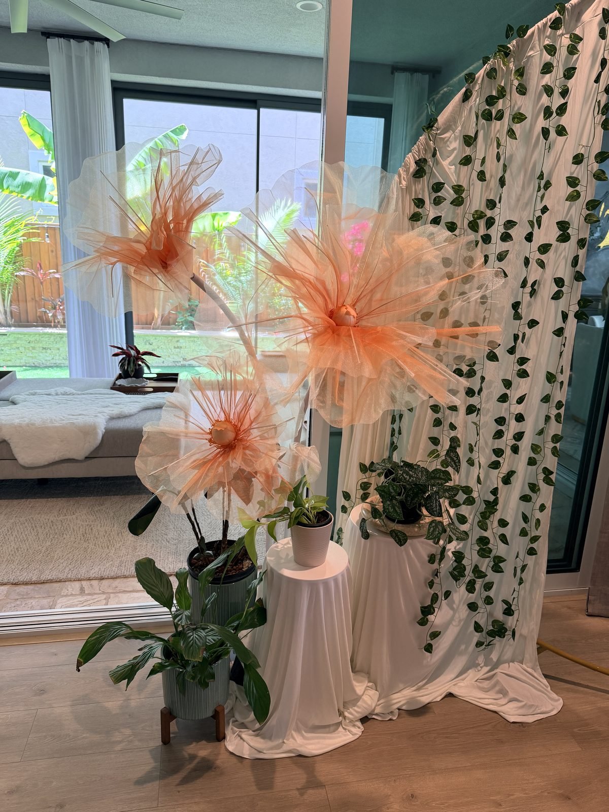 Oversized peach tulle stem flowers and ivy backdrop styled by BlissHub Events